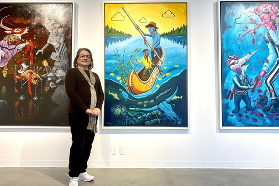 Person stands in front of large colorful paintings in a gallery