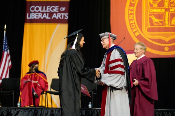 A graduate shakes Dean Coleman's hand as she crosses the stage