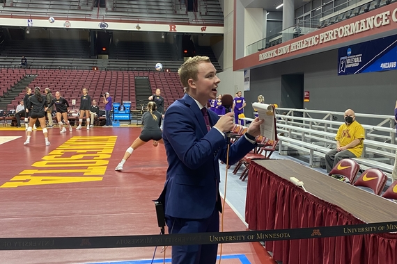 Connor O'Neal reporting from the Minnesota volleyball court with a microphone and notepad in his hand