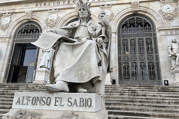 Statue of Alfonso X of Castile, seated with scroll in hand. Outside on steps leading up to Biblioteca Nacional, Madrid. 