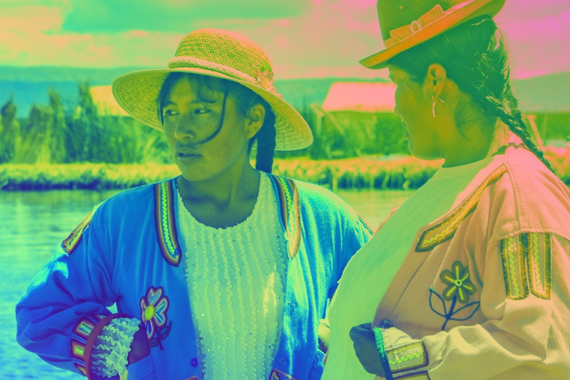 A woman wearing a straw hat, a blue embroidered jacket, and a white blouse stands outdoors near water, looking to the side.