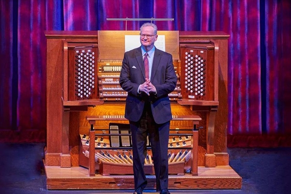 Dean Billmeyer stands in front of an organ. 