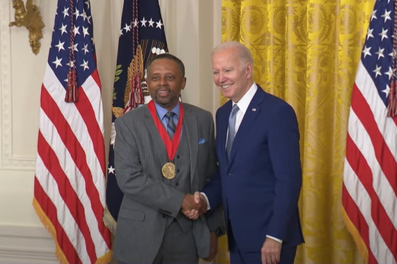 A man wearing a medal shakes President Joe Biden's hand.