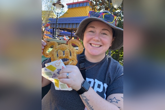 Elizabeth Hockensmith holds a Mickey Mouse-shaped churro and smiles at the camera