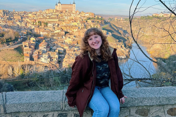 Emma Nelson sitting on ledge, overlooking Toledo cityscape