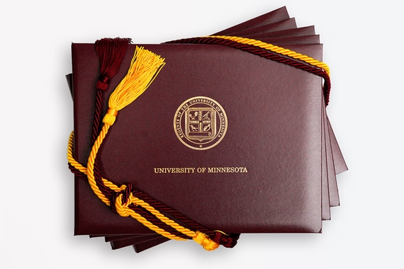 Stack of diploma covers with cords draped across the corners