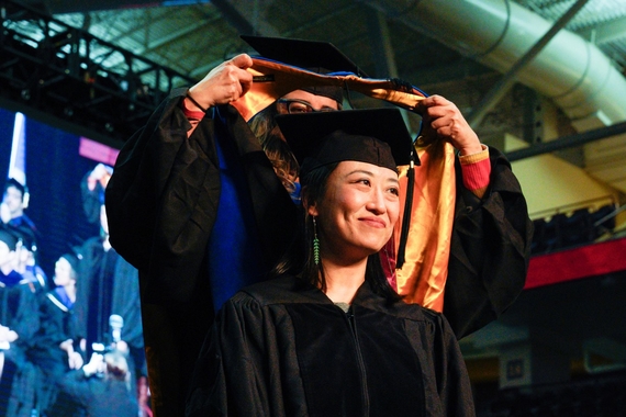 Image of grad student being hooded at a commencement ceremony