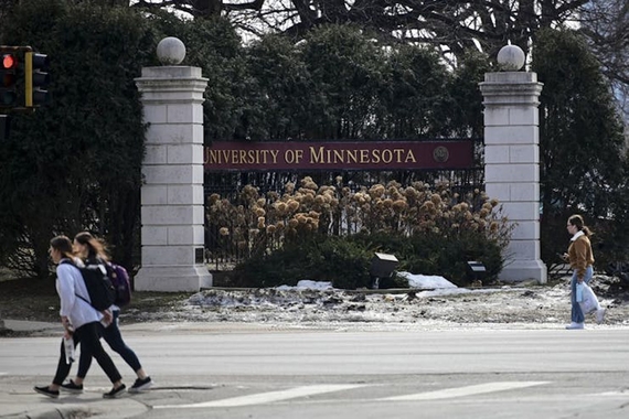 Pedestrians walk past a University of Minnesota sign along University Avenue.
