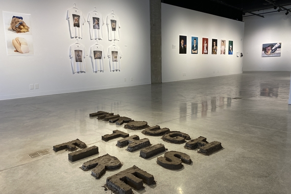 Gallery view of artworks in Nash Gallery. On the floor spelled out in dirt it says "Through this fire"