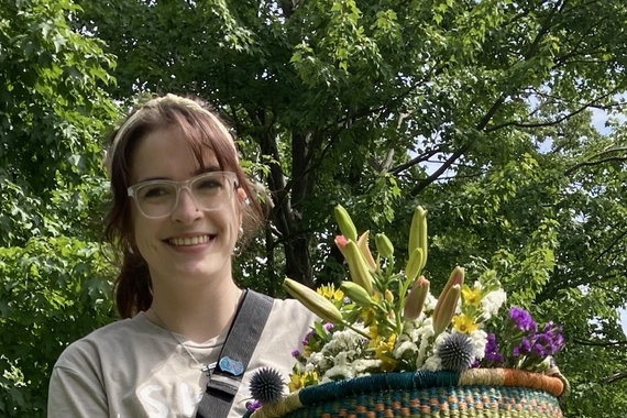 Photo of Julia Knudten outdoors holding a basket of plants