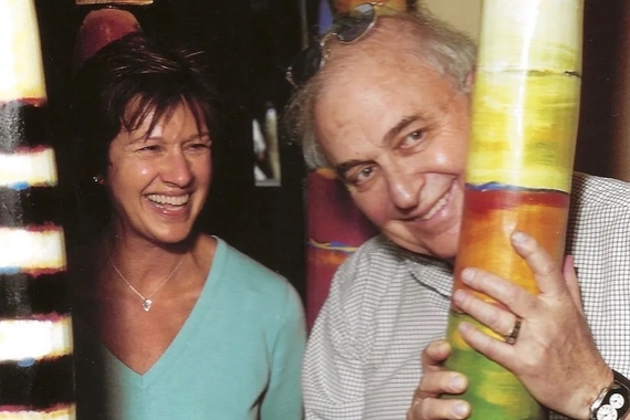 Two smiling people surrounded by colorful artwork.