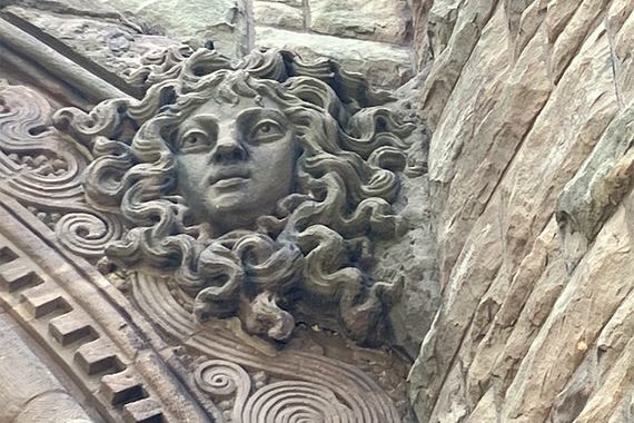 Photo of stone carving on building: face with snakes surrounding