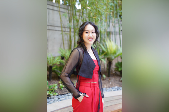 Naomi Ko standing outside in a red dress and black jacket