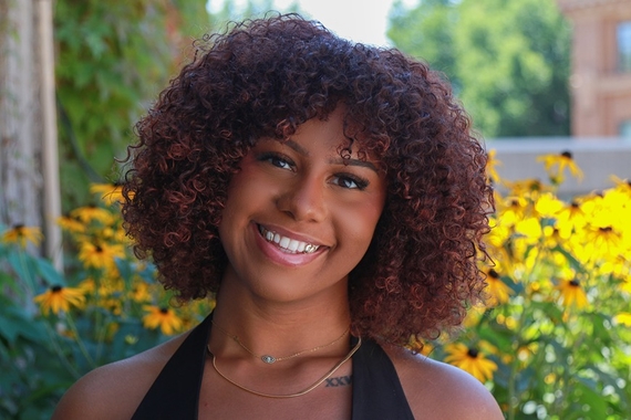 Headshot of Onteya Zachary smiling outdoors, with yellow flowers in the background.