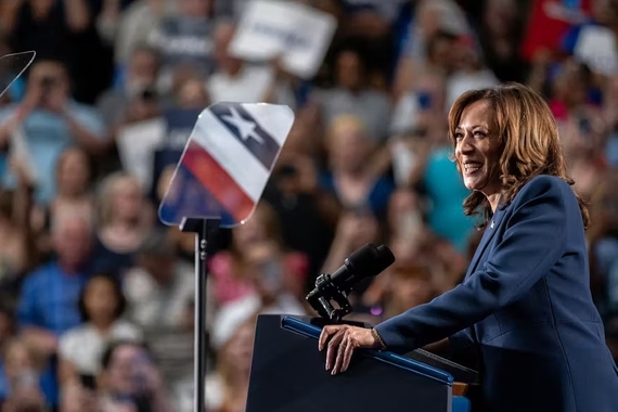 Vice President Kamala Harris, a Black and South Asian woman in a navy blue blazer, speaks at a campaign rally