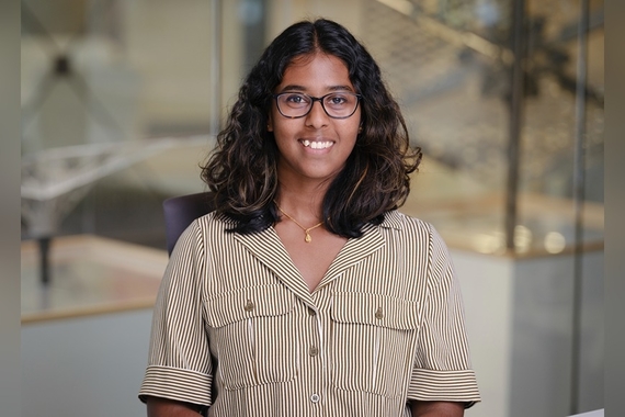 Mathi Manavalan, a person with light brown skin, glasses, and shoulder-length dark hair