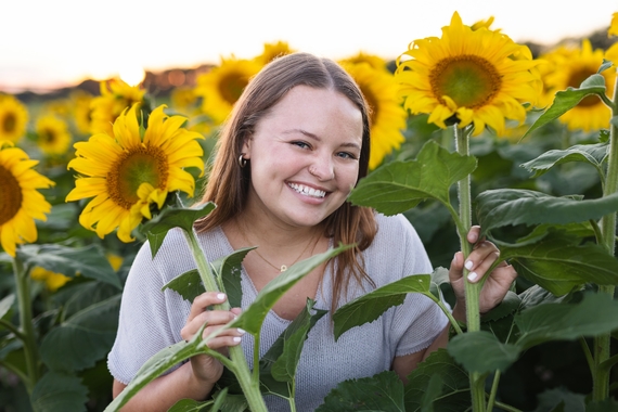 Phoebe Gadient smiles in a field of sunflowers
