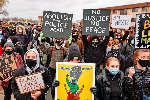 Protesters in face masks holding signs that read: Abolish the Police ACAB, No Justice No Peace, Am I Next?, Black Lives Matter, and other slogans. 