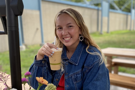 Image of Drue Schwitters drinking ice coffee outside at a table