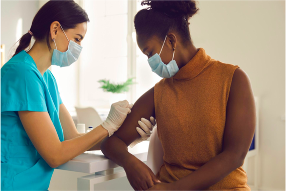A black woman getting a covid vaccine by a nurse 