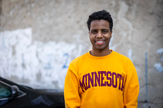Abdulaziz Mohamed poses for a photo with a Minnesota yellow sueter