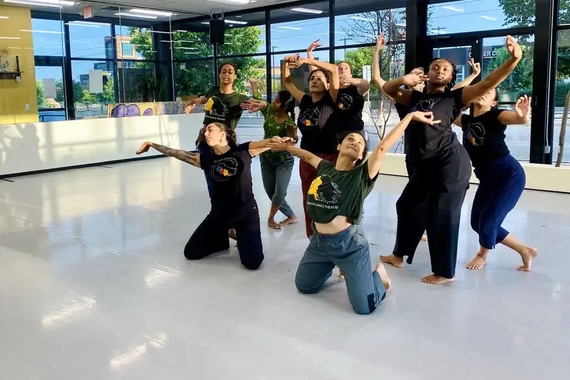 Nine BIPOC women and femme dance artists pose during a dance in a sunny studio