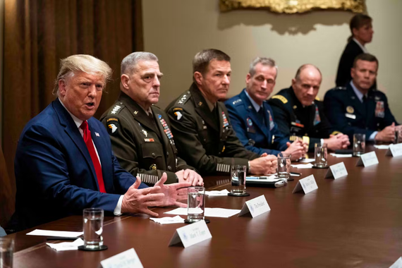 Donald Trump sits at a table with military leaders in uniform. 