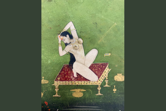 An illustration of kedara ragini: a naked woman is positioned on a low throne, situated in a green landscape. 