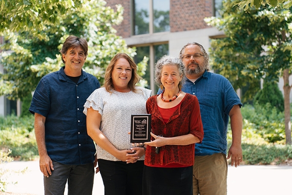 Members of WAC standing outside holding an award plaque.