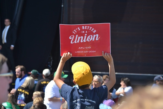 A youngster wearing a yellow cap holds up a red pro-union sign 