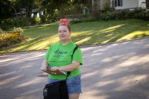 Rae Peter with Minnesota Voice pauses for a portrait while door knocking a neighborhood in Winona