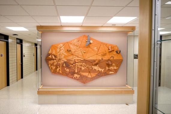 Large clay-colored, wall-mounted ceramic installation inside a display case