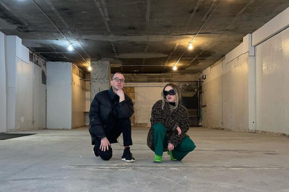 Two people kneel towards the camera in a large empty commercial space