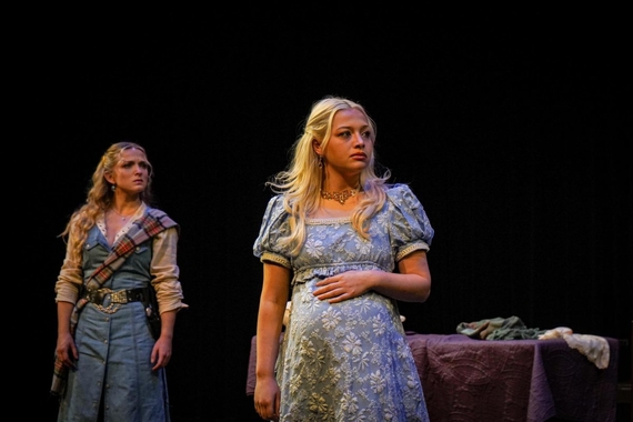 Two female actors looking away. Black background and a table in the background.