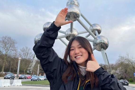 Kaia Brands, a young woman of color, gives a thumbs-up in front of a metal statue