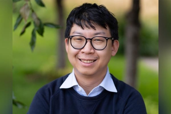 Kevin Luo, an Asian man wearing glasses and a button-up and sweater, smiles for the camera