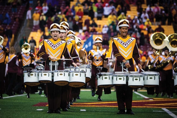 Members of the UMN Marching Band drumming during a performance