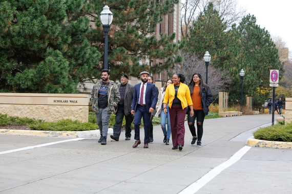MLK Program founding member Dr. John Wright, distinguished alumnus Regent Abdul Omari, and assistant director Melanie Johnson walk with student participants along Scholars Walk.