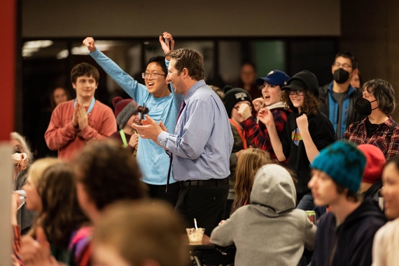 A group of students celebrates with claps and fist pumps after winning their Middle School Debate.