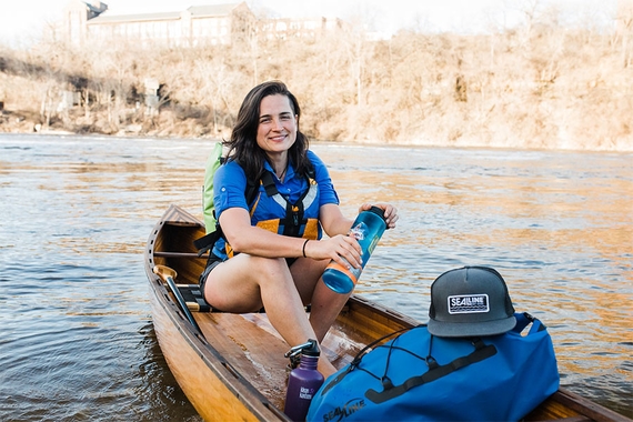 Natalie Warren, seated in a canoe beached on the shore of the Mississippi River. She has light skin and long, straight black hair.