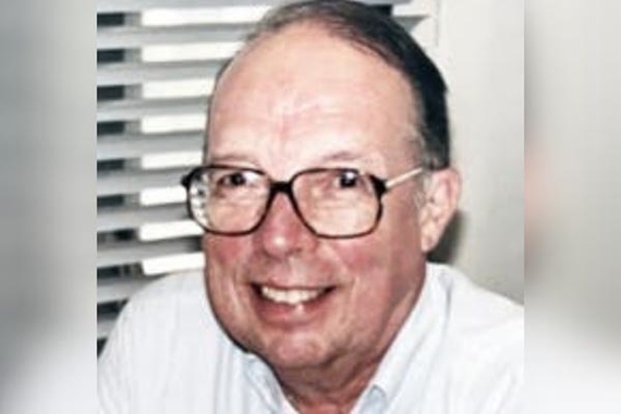 William H. Flanigan, an older white man with graying black hair and glasses, smiles