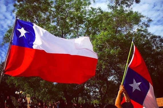 crowd of people holding two Chilean Flags, one is upside down