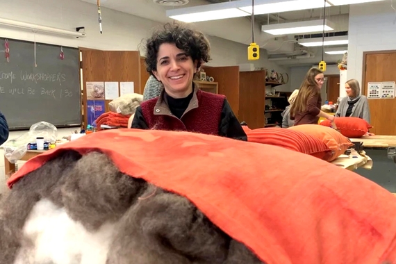 Rotem Tamir stands over a massive pile of pillow stuffing in a classroom