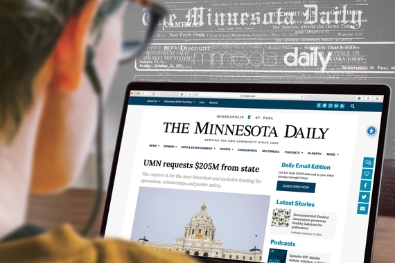 A person looks onto their computer screen which displays The Minnesota Daily's homepage