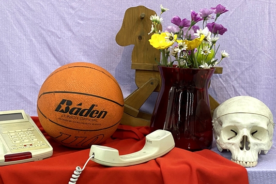 Still life display with telephone, basketball, skull, and flowers on purple and red fabric