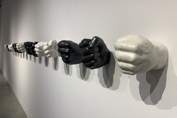 ow of oversized ceramic hands clenched into fists, alternating left and right in pairs of black and white, attached to the wall at the wrists