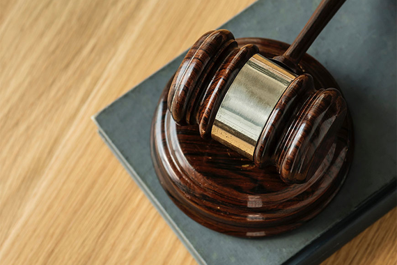 Photo of a wooden gavel with a sounding block resting on a wooden desk