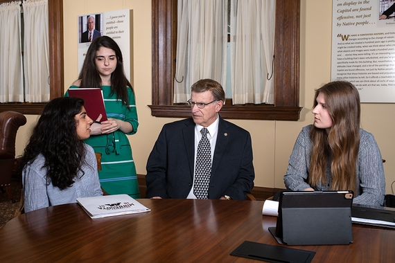 Three students meet with State Representative in the Minnesota capitol building.