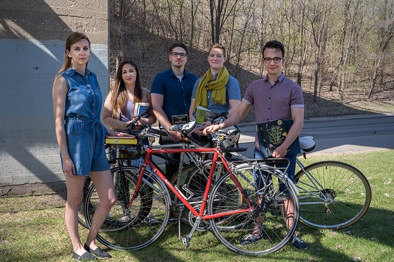 Five graduate students gather around bikes down by the Mississippi river.
