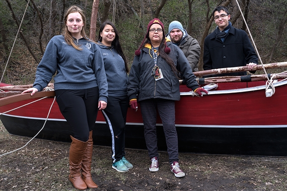 Five students stand around a large traditional ocean fishing boat.